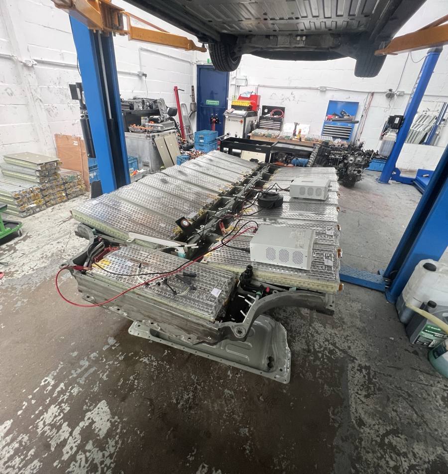 Tesla Model S battery pack opened on the workshop floor under the lift